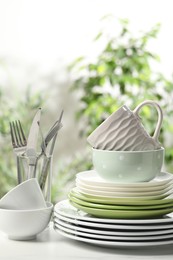 Photo of Beautiful ceramic dishware, cutlery and cup on white table outdoors