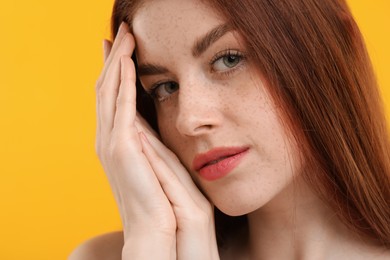 Portrait of beautiful woman with freckles on yellow background, closeup