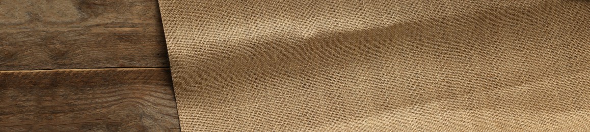 Photo of Burlap fabric on wooden table, top view