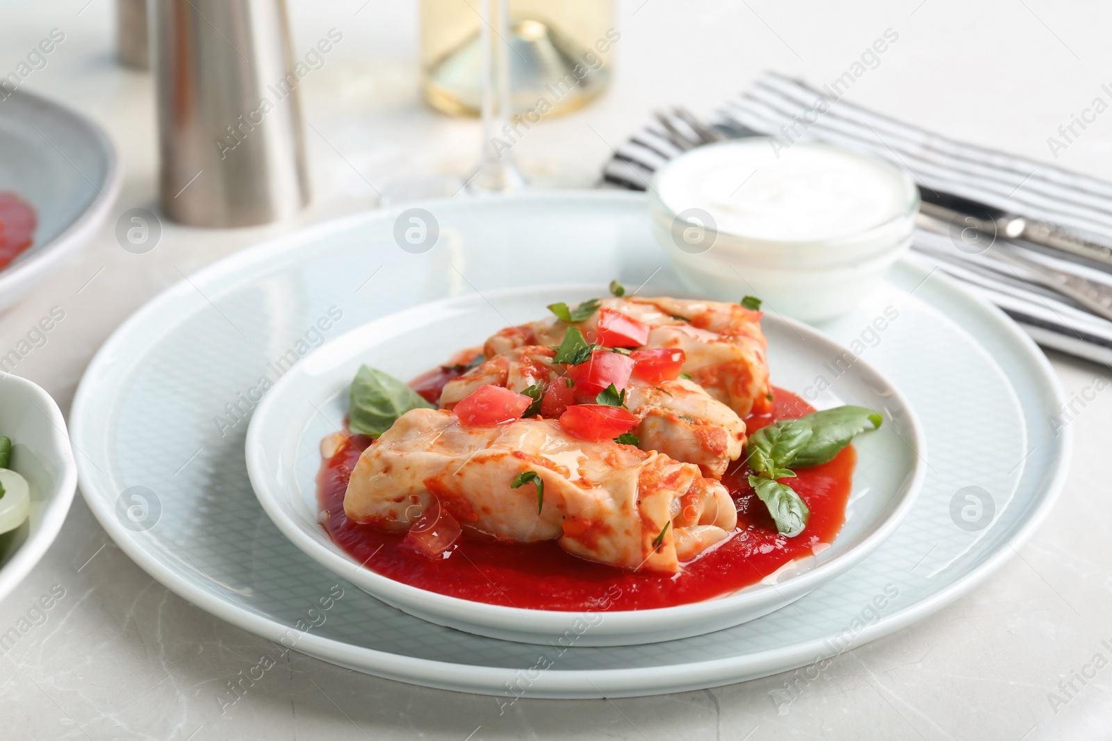 Photo of Plate with stuffed cabbage leaves in tomato sauce on table