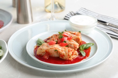 Photo of Plate with stuffed cabbage leaves in tomato sauce on table