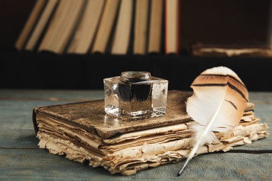 Photo of Feather pen, inkwell and book on blue wooden table