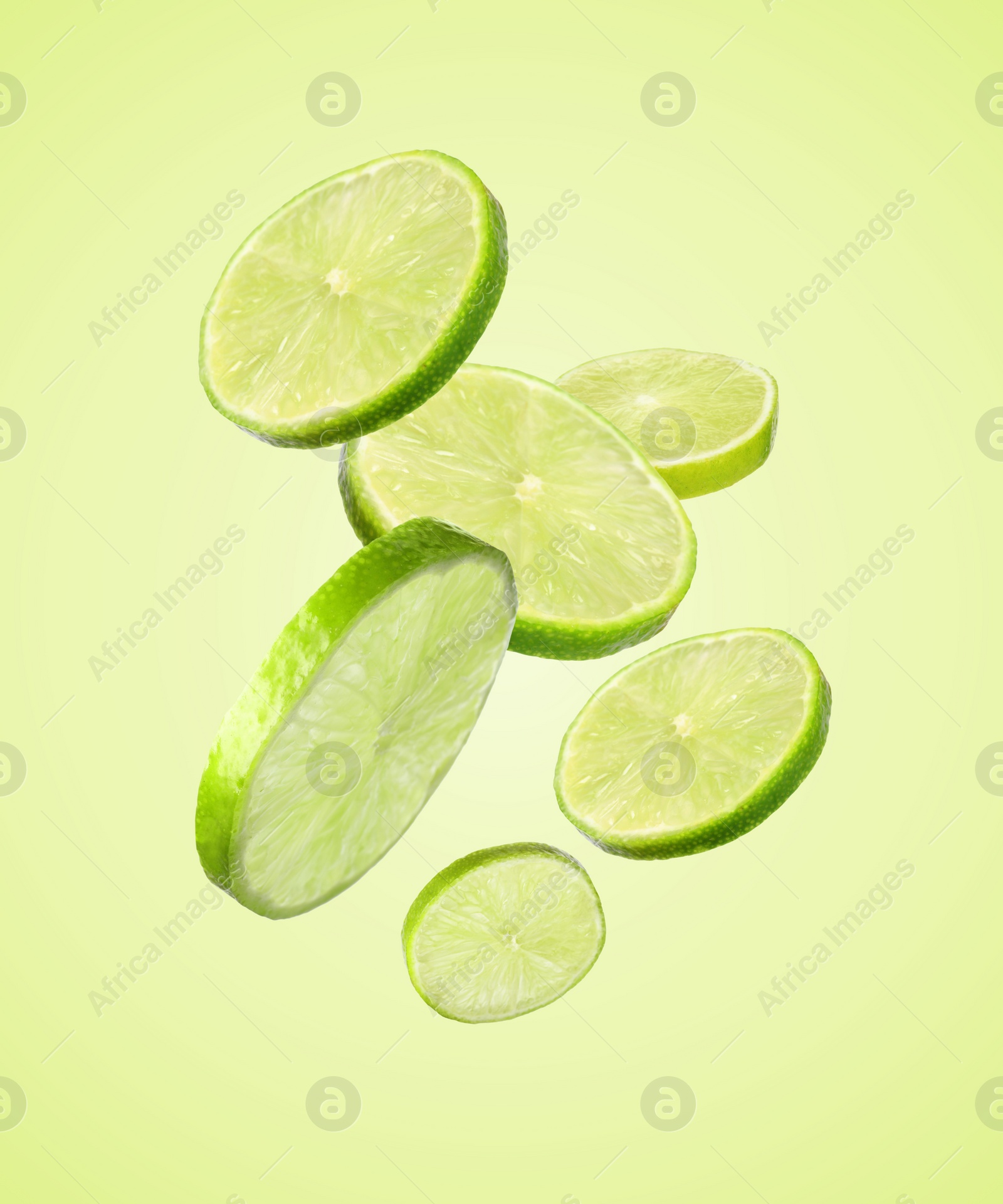 Image of Fresh lime slices falling on light green background