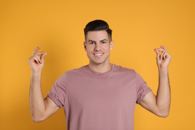 Photo of Handsome man snapping fingers on yellow background