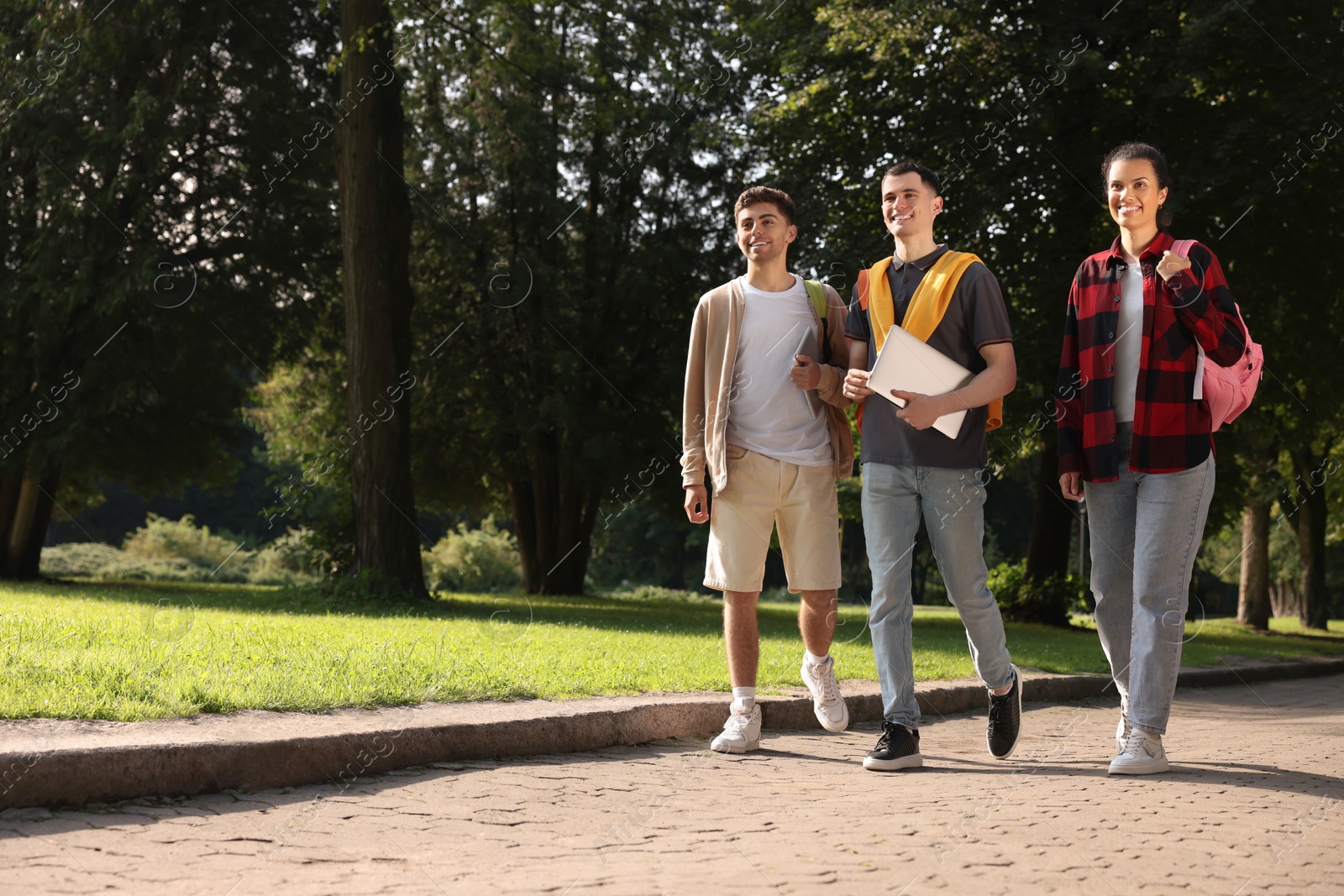 Photo of Happy young students walking together in park on sunny day