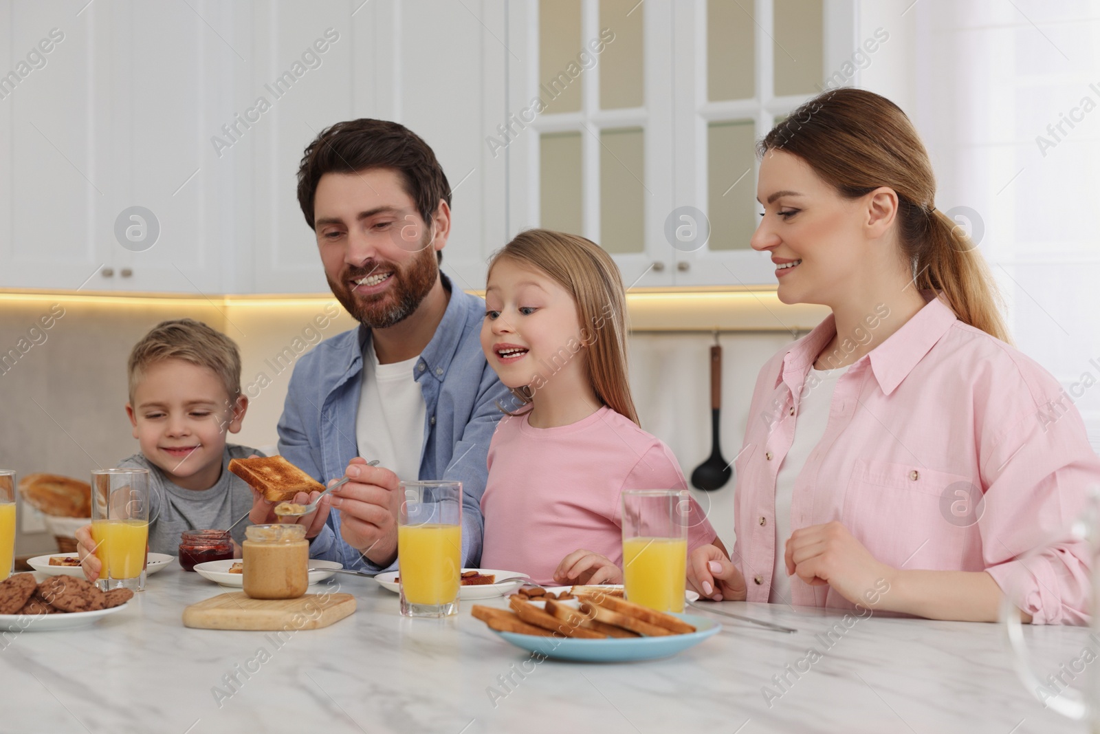 Photo of Happy family having breakfast at table in kitchen