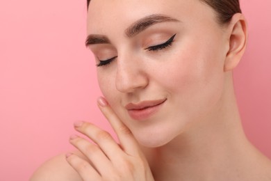 Makeup product. Woman with black eyeliner and beautiful eyebrows on pink background, closeup