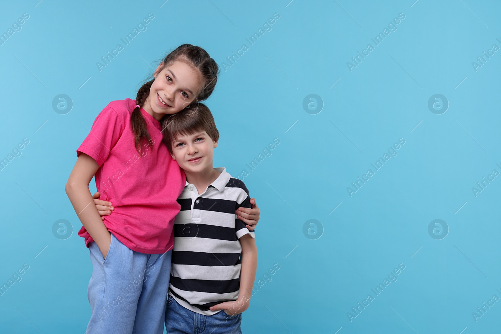 Photo of Happy brother and sister hugging on light blue background, space for text