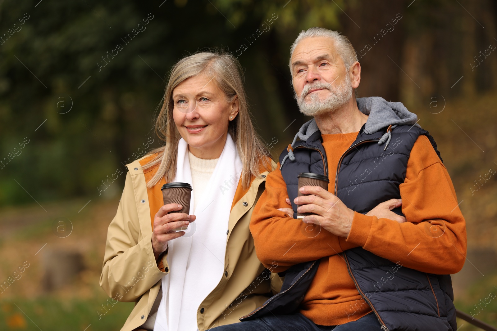 Photo of Affectionate senior couple with cups of coffee in autumn park