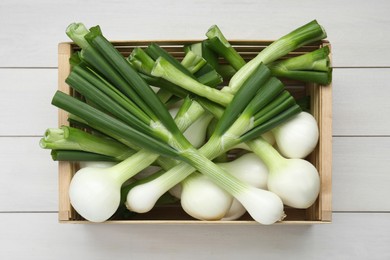 Photo of Crate with green spring onions on white wooden table, top view