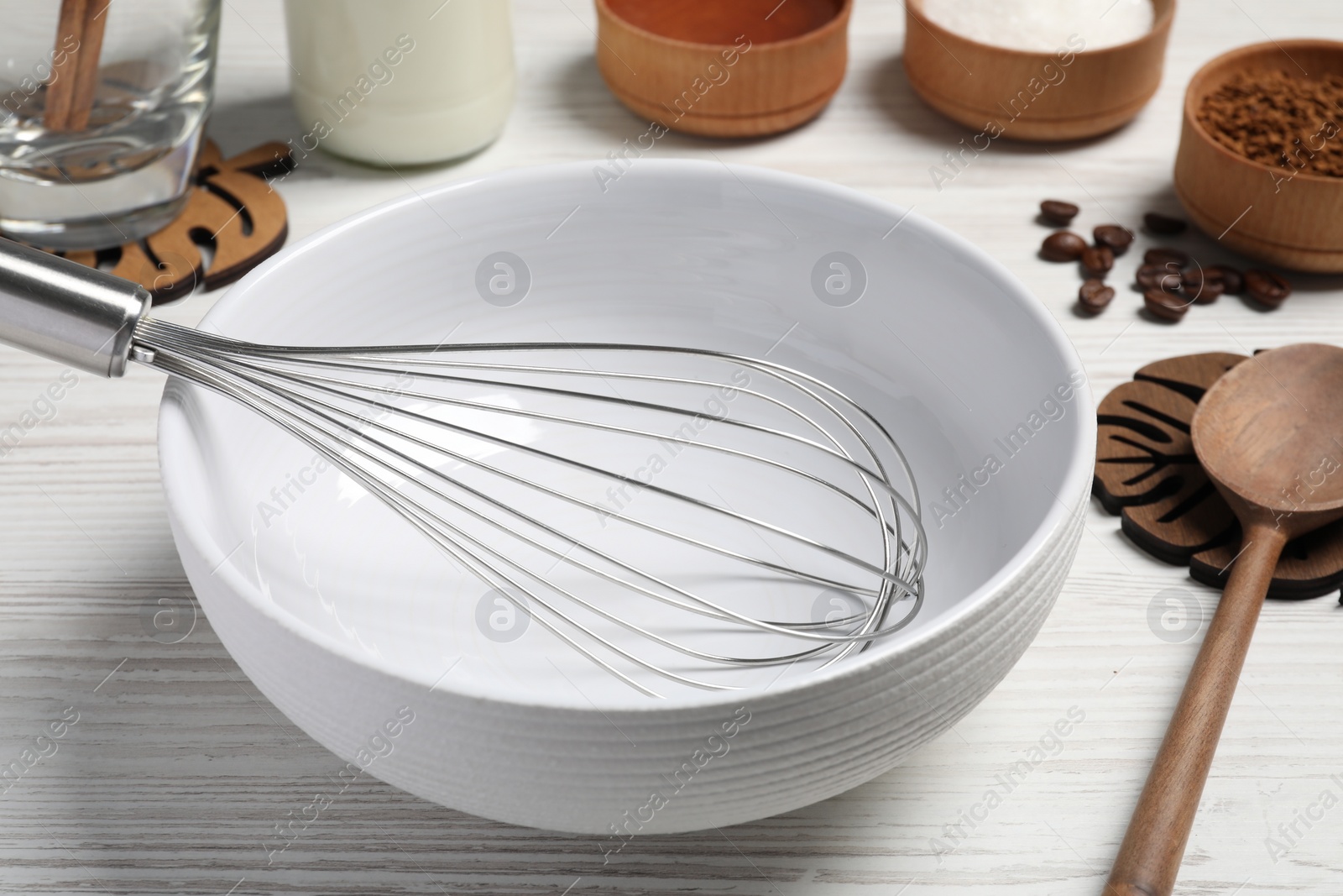 Photo of Bowl with whisk and coffee on white wooden table, closeup