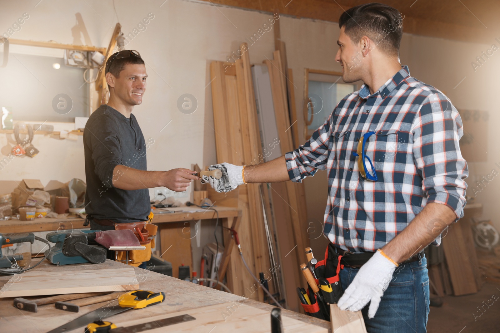 Photo of Carpenter giving tool to colleague in workshop