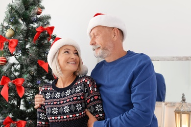 Photo of Mature couple in Santa hats at home. Christmas celebration