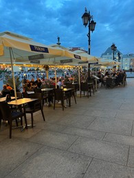 Photo of WARSAW, POLAND - JULY 15, 2022: Outdoor cafe terrace on Crowded Old Town Market Place in evening