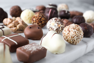 Different tasty chocolate candies on white marble board