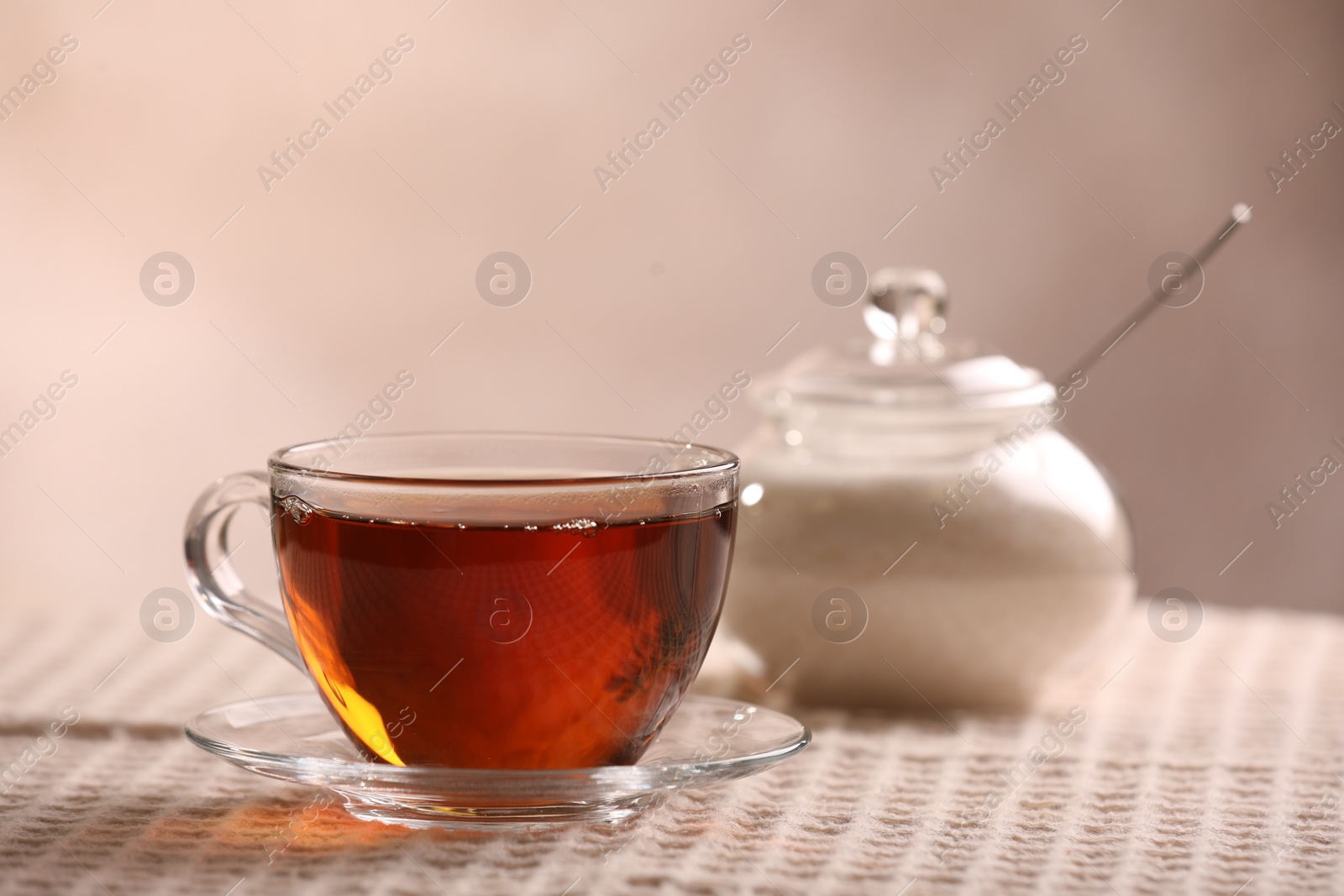 Photo of Aromatic tea in cup, saucer and sugar on table