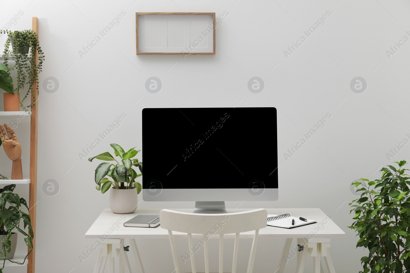 Photo of Spacious workspace with desk, chair, computer and potted plants at home