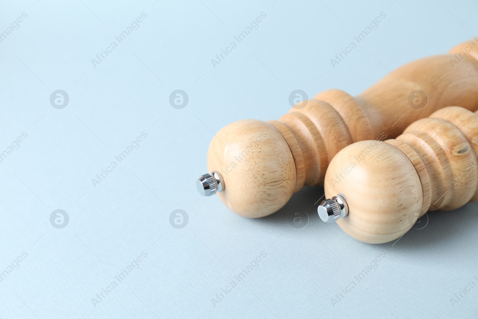 Photo of Wooden salt and pepper shakers on light background, space for text