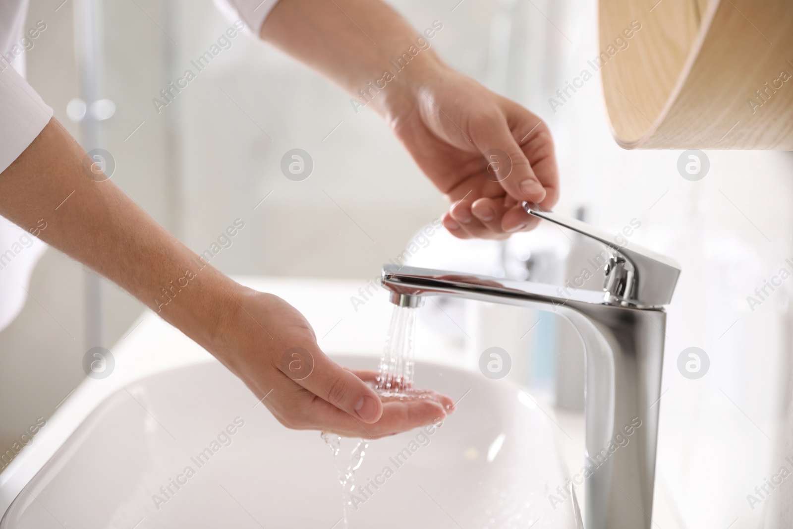 Photo of Man washing hands over sink in bathroom, closeup