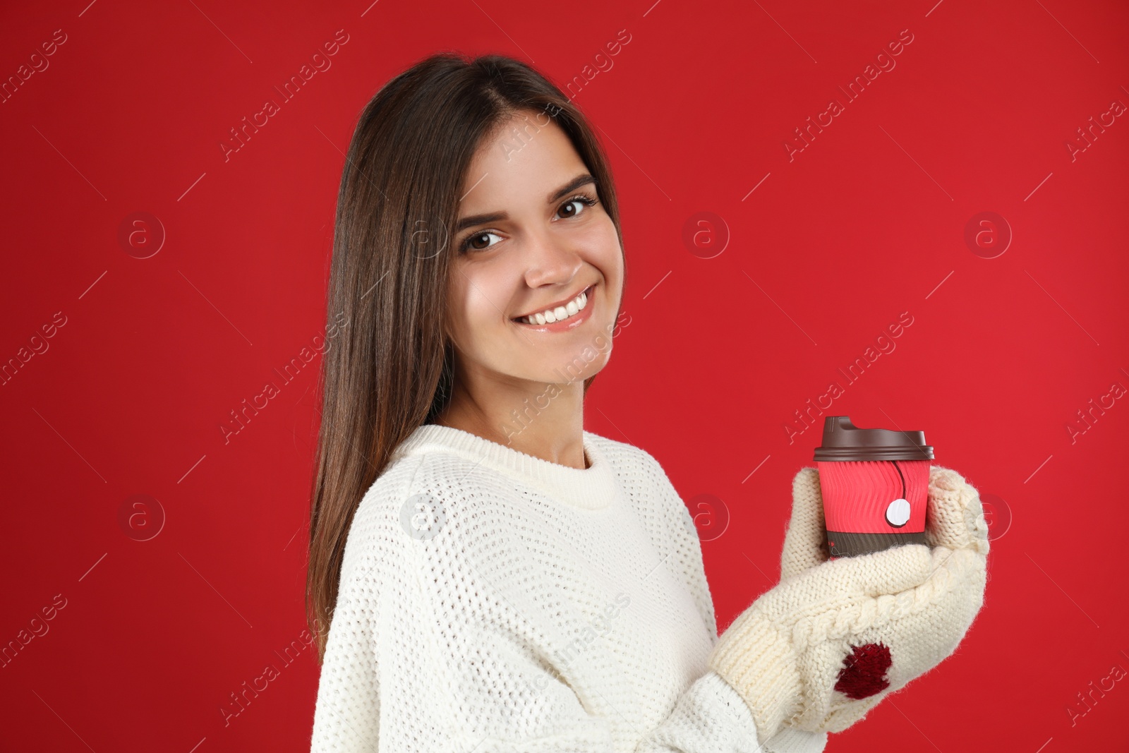 Photo of Happy beautiful woman with paper cup of mulled wine on red background