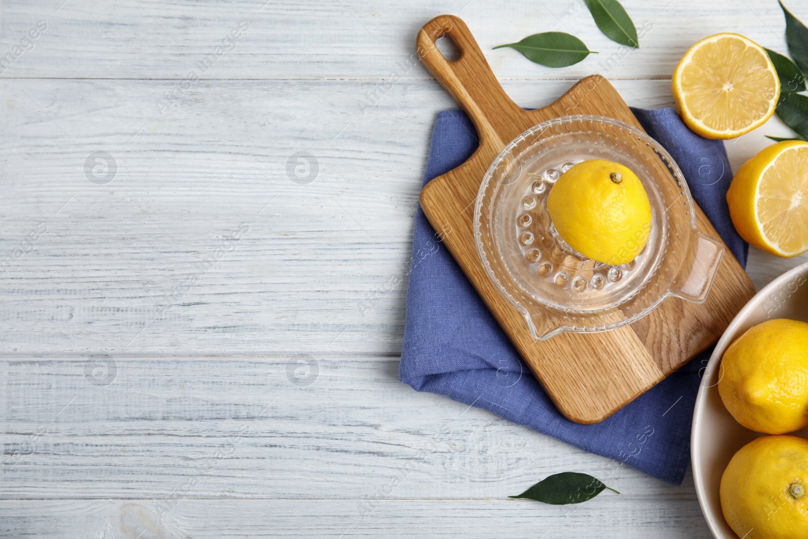 Photo of Glass squeezer and fresh lemons on white wooden table, flat lay. Space for text