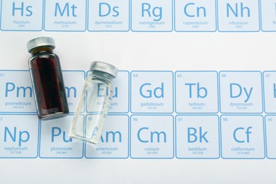 Photo of Bottles on periodic table of chemical elements, flat lay