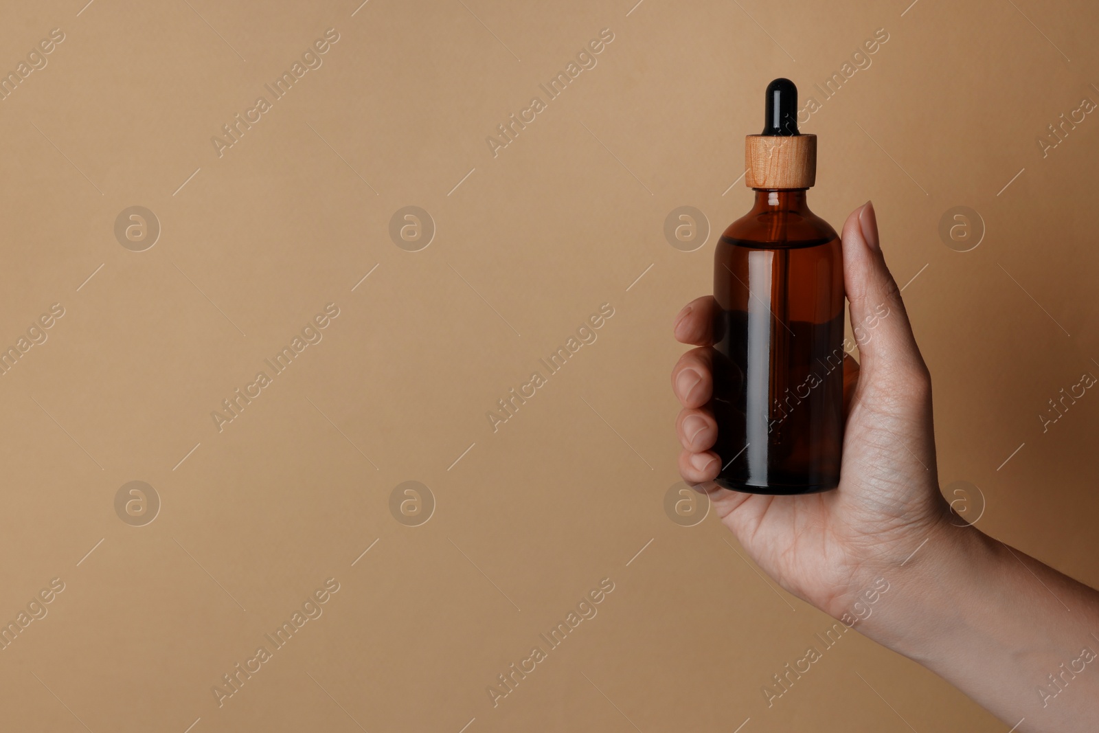 Photo of Woman holding bottle of cosmetic product on beige background, closeup. Space for text