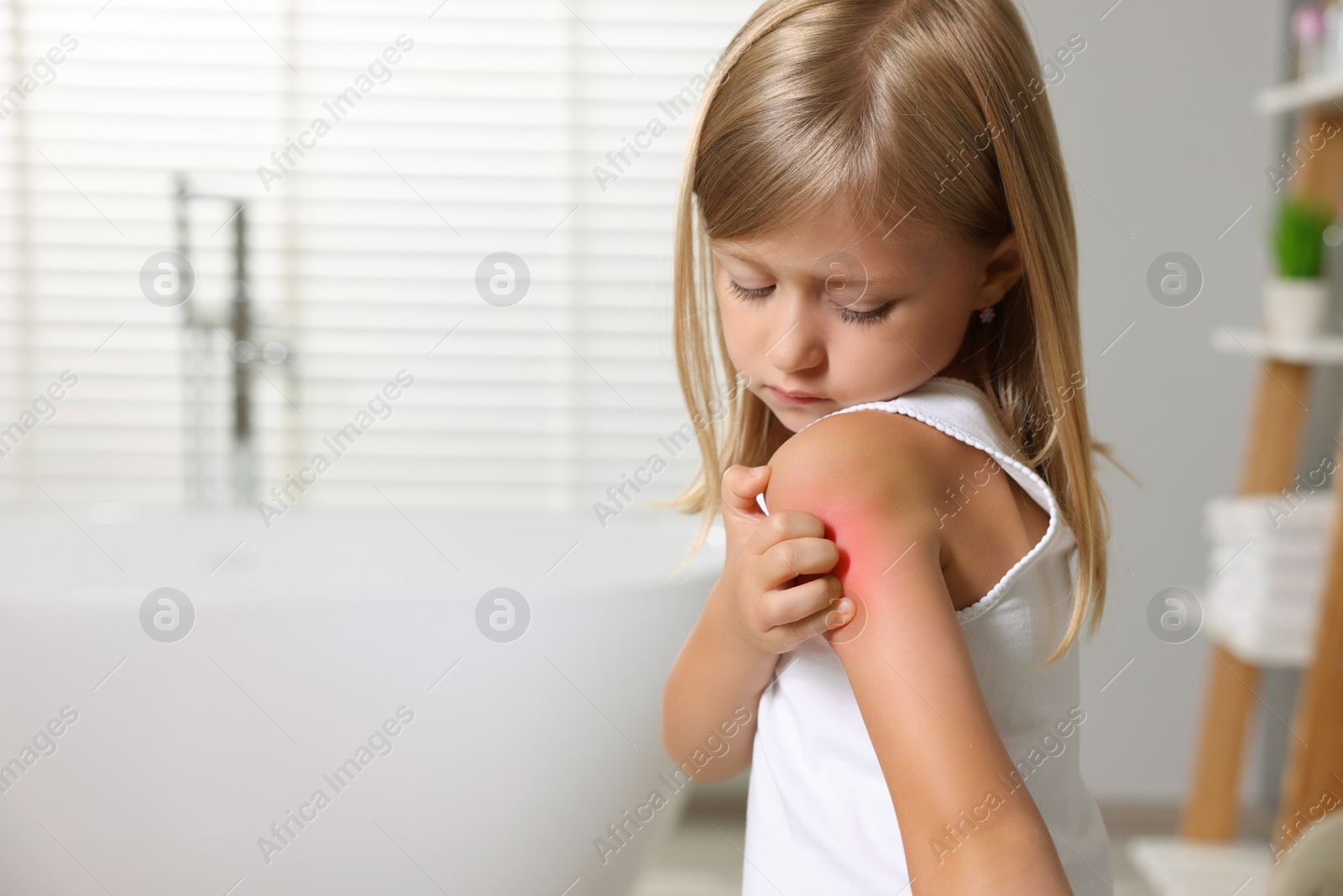 Photo of Suffering from allergy. Little girl scratching her shoulder in bathroom, space for text