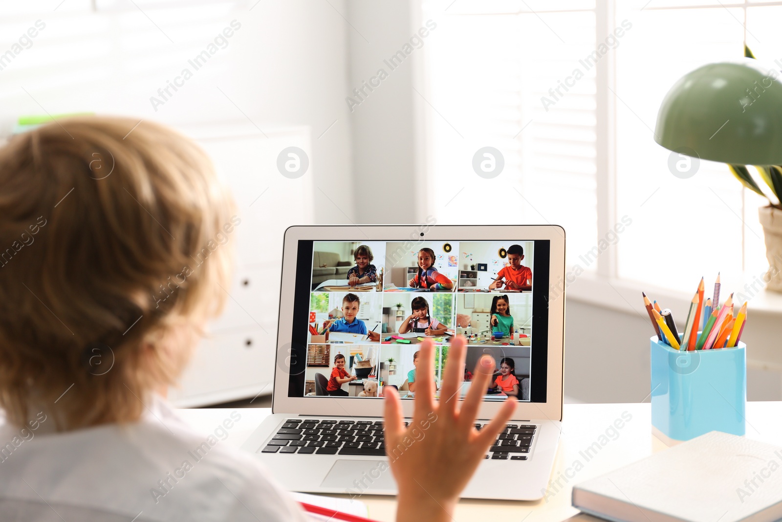 Photo of Little boy studying with classmates via video conference at home. Distance learning during COVID-19 pandemic