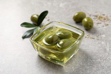 Photo of Glass bowl with fresh olive oil on light grey table