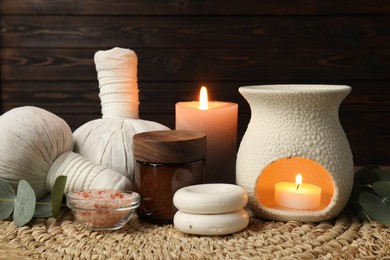 Photo of Aromatherapy. Scented candles and spa products on wicker mat, closeup