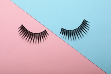 Artificial eyelashes on color background, top view