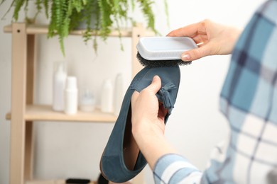 Woman taking care of stylish shoe indoors, closeup