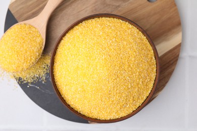 Photo of Raw cornmeal in bowl and spoon on white table, top view