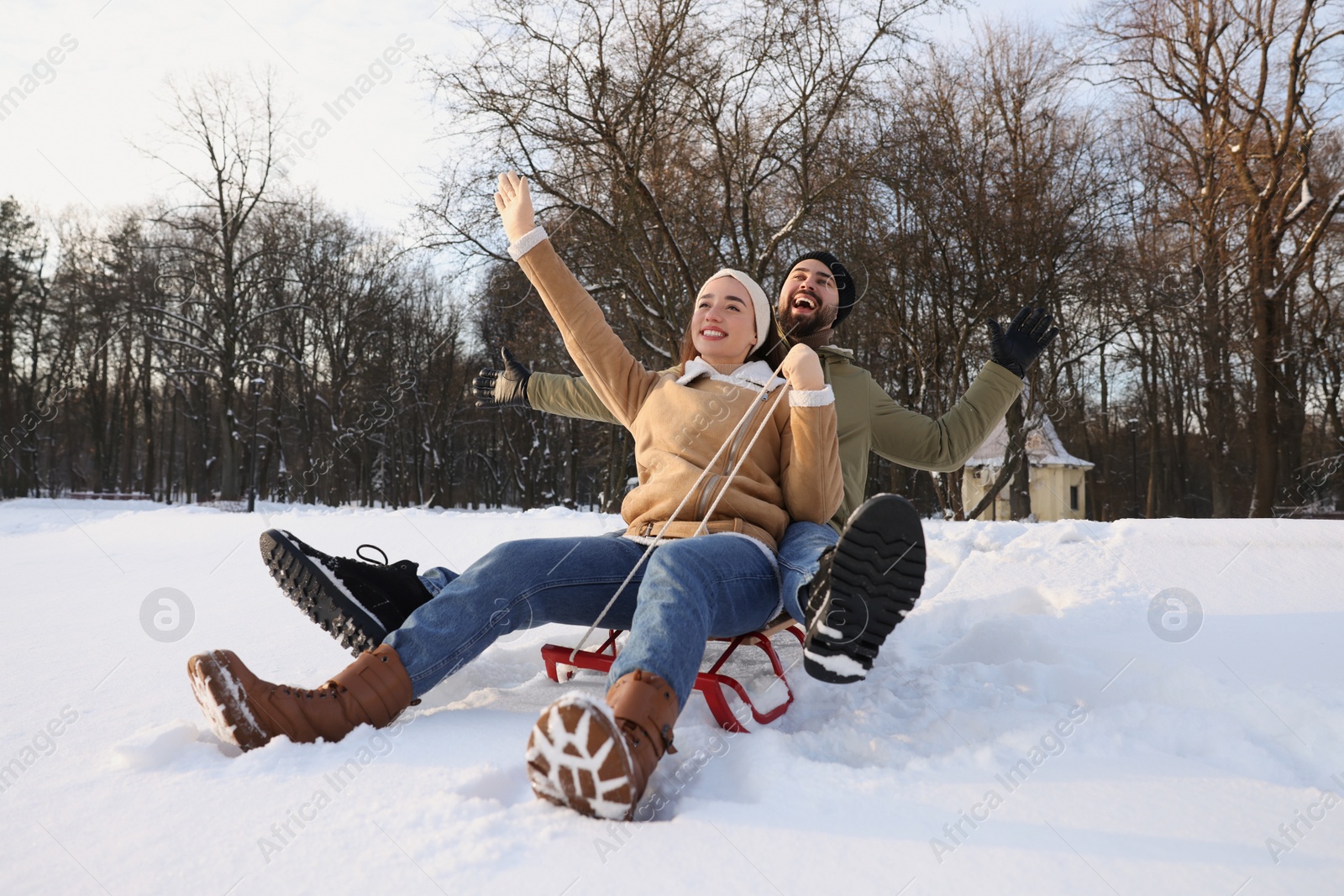 Photo of Happy young couple sledding outdoors on winter day