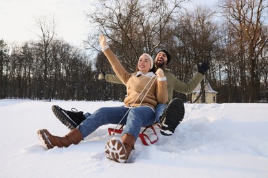 Happy young couple sledding outdoors on winter day