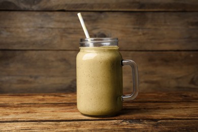 Mason jar with delicious fruit smoothie on wooden table