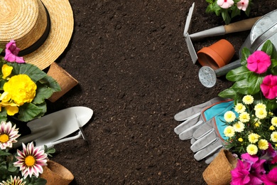 Photo of Flat lay composition with gardening tools and flowers on soil, space for text