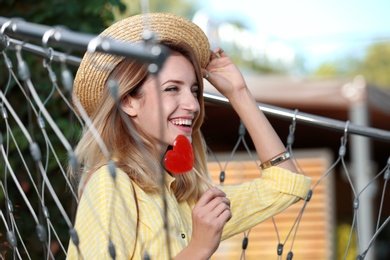 Photo of Young woman with candy relaxing in hammock chair outdoors