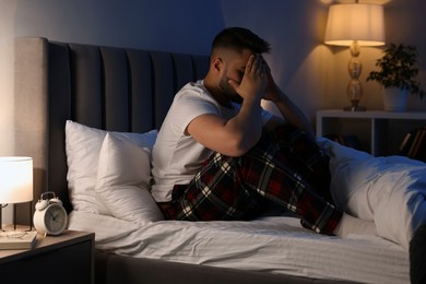 Photo of Man covering face with hands on bed. Insomnia problem