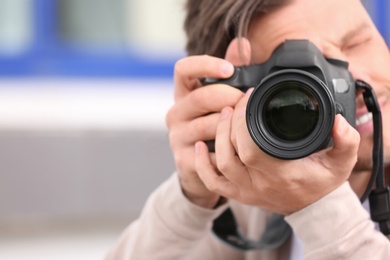 Photo of Male photographer with professional camera on blurred background. Space for text