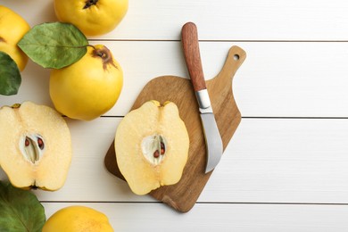 Photo of Tasty ripe quince fruits and knife on white wooden table, flat lay. Space for text