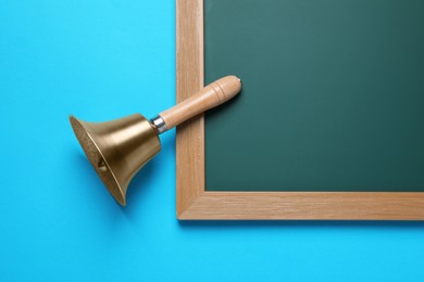 Photo of Golden bell and green chalkboard on light blue background, flat lay. School days