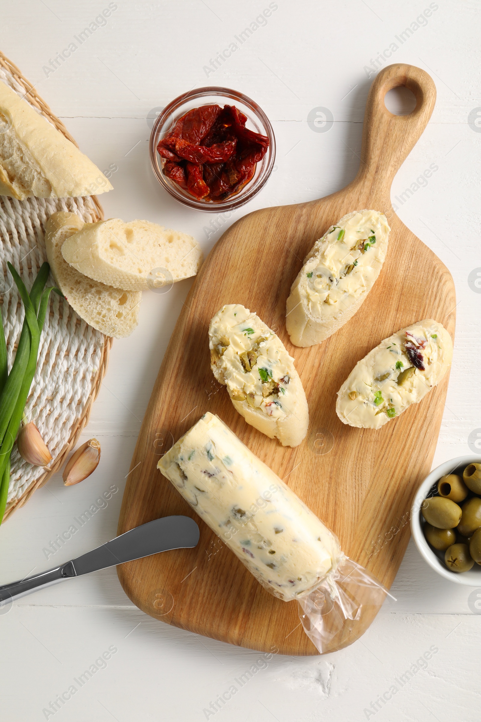 Photo of Tasty butter, bread and other ingredients on white wooden table, top view