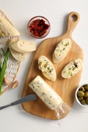 Photo of Tasty butter, bread and other ingredients on white wooden table, top view