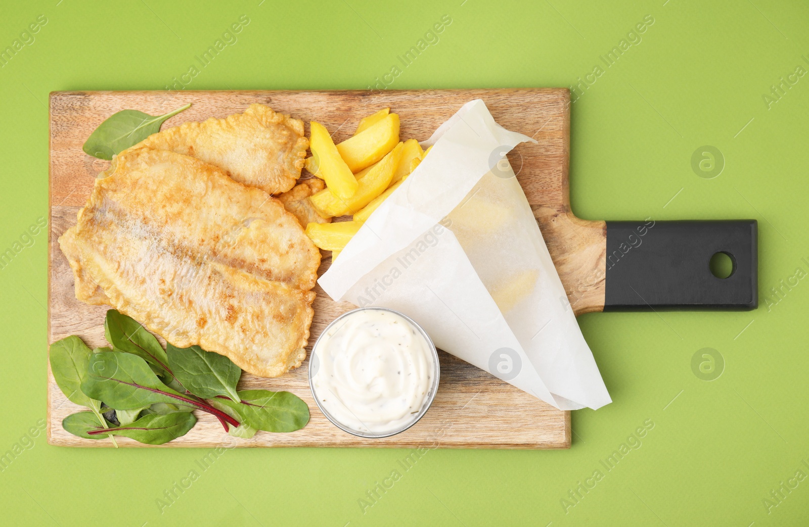 Photo of Delicious fish and chips with tasty sauce and mangold on green table, top view