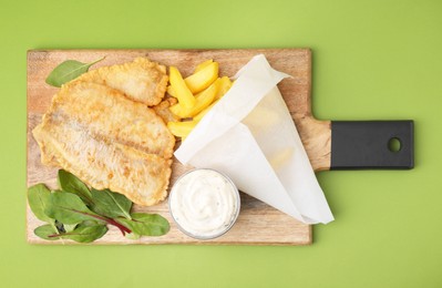 Delicious fish and chips with tasty sauce and mangold on green table, top view