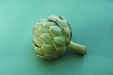 Photo of Whole fresh raw artichoke on green background. closeup
