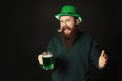Photo of Bearded man with green beer on black background. St. Patrick's Day celebration