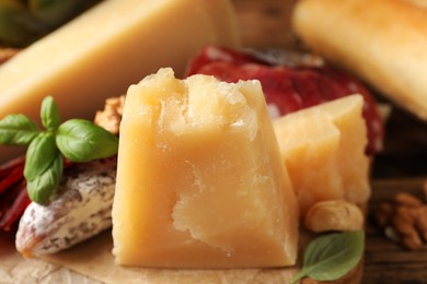Photo of Delicious parmesan cheese, sausage and basil on wooden table, closeup